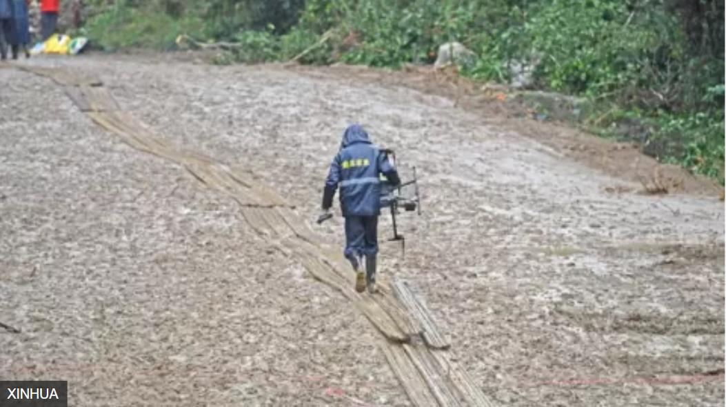 广西梧州藤县中国东航MU5735航班坠落事故坠落现场无人机操作人员在铺上竹子的泥泞路面上行进 ...