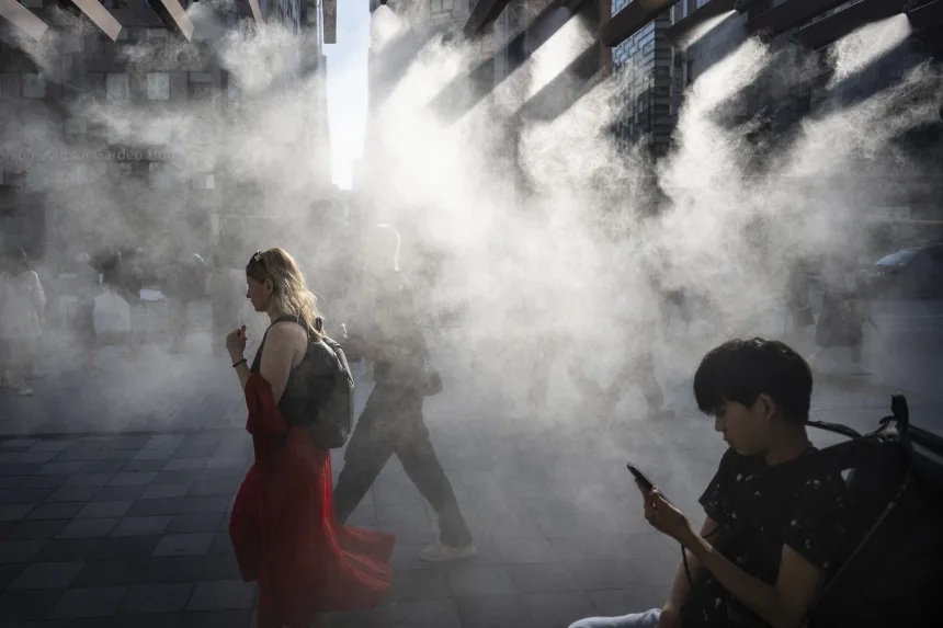 日本东京，炎热的天气里，人们走在水雾系统下方降温